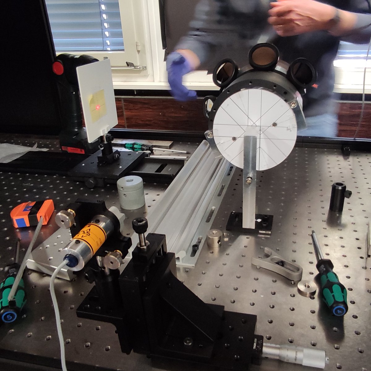 Experts at CERN have recently aligned eight spherical mirrors for the KTAG detector, which collects the Chereknov light produced by the new CEDAR-H. Here you can see a small laser in the foreground, four mirrors on a support cylinder, and the target (with laser spot) on the left.