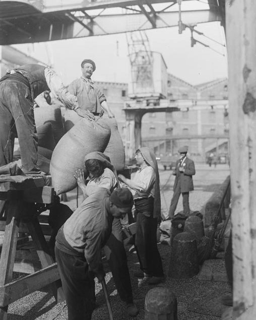 Cinc persones descarreguen sacs de mercaderia al Port de Barcelona. De fons es poden apreciar dues grues transportadores de grans dimensions.

 [01/01/1920-31/12/1930]

📷 Sagarra i Plana, Josep Maria

<a href="/arxiunacional/">Arxiu Nacional</a>

#port #portdebarcelona #bcnmoltmes #historiaambcolor