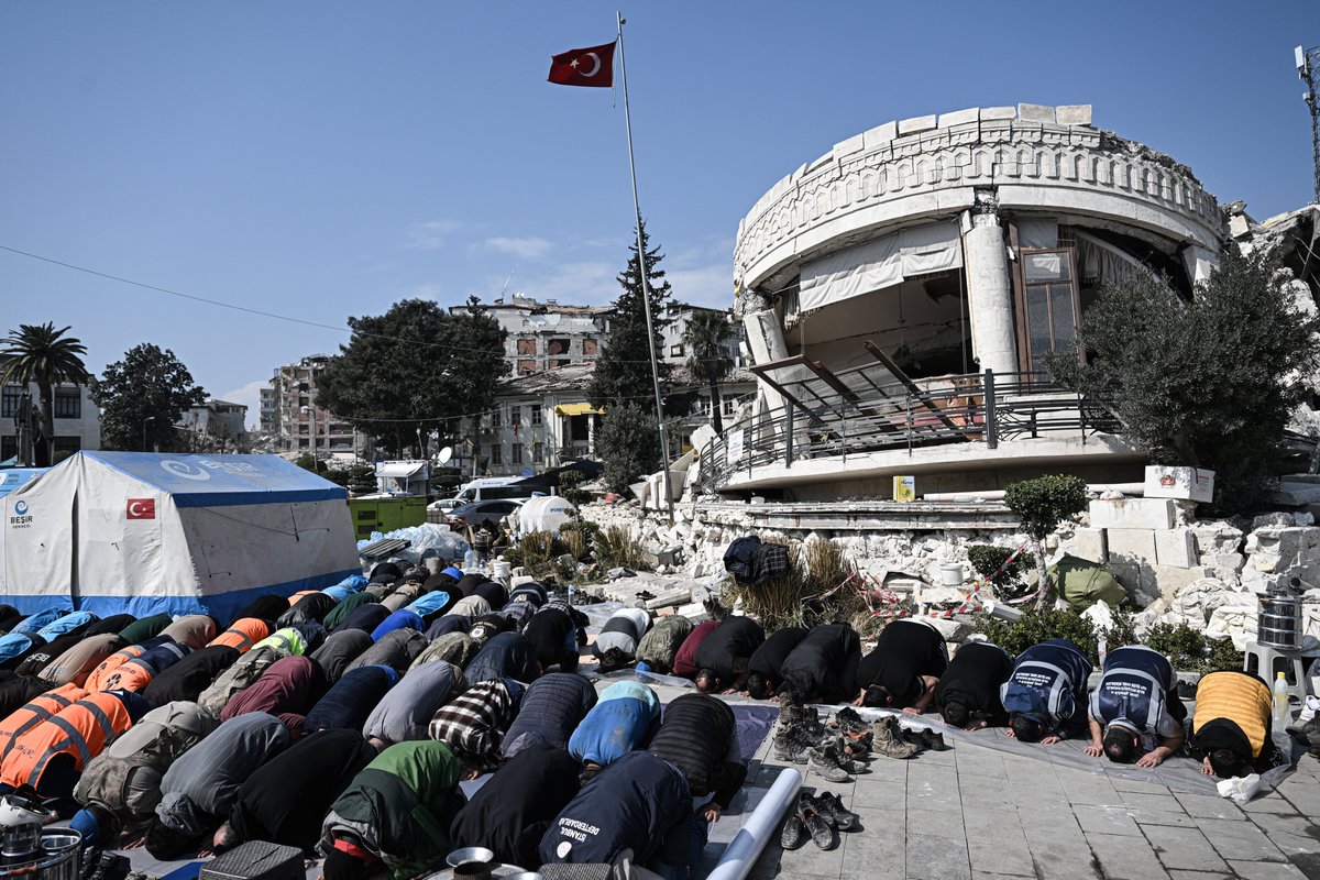dailyislamist's tweet photo. 📸 | Deprem bölgesi Hatay'da gönüllüler, depremzedeler, polisler ve Mehmetçiğin de katılımıyla eski meclis binası önünde cuma namazı eda edildi. https://t.co/cIguean5Ky