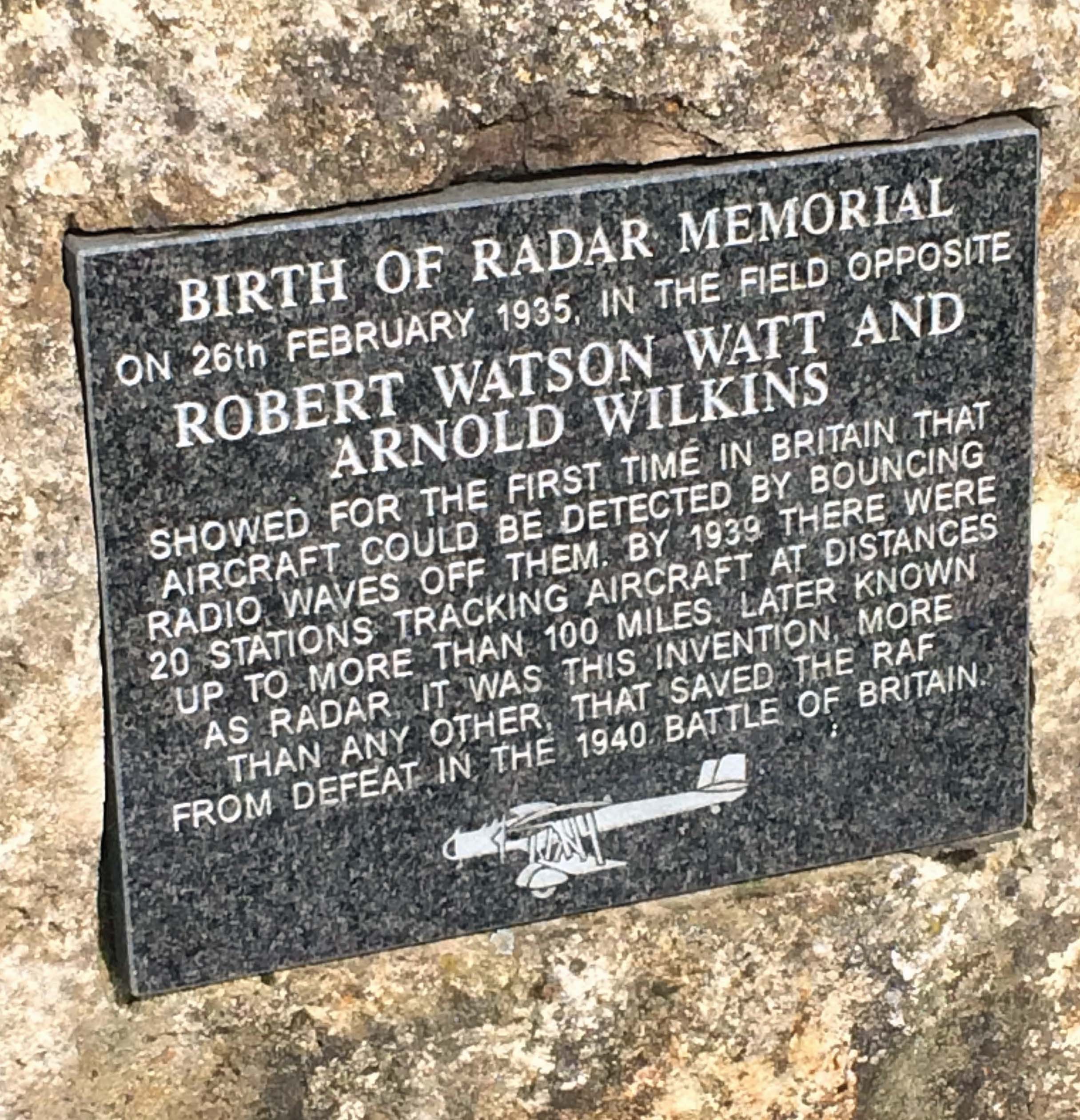 A square piece of grey slate set in a stone wall. The slate is engraved to mark the 'Birth of Radar' memorial. An experiment conducted by Robert Watson Watt and Arnold Wilkins known as the Daventry Experiment took place on 26 February 1935 and the words say the experiment 'showed for the first time in Britain that aircraft could be detected by bouncing radio waves off them. By 1939 there were 20 stations tracking aircraft at distances up to more than 100 miles. Later known as radar, it was this invention more than any other that saved the RAF from defeat in the 1940 Battle of Britain.