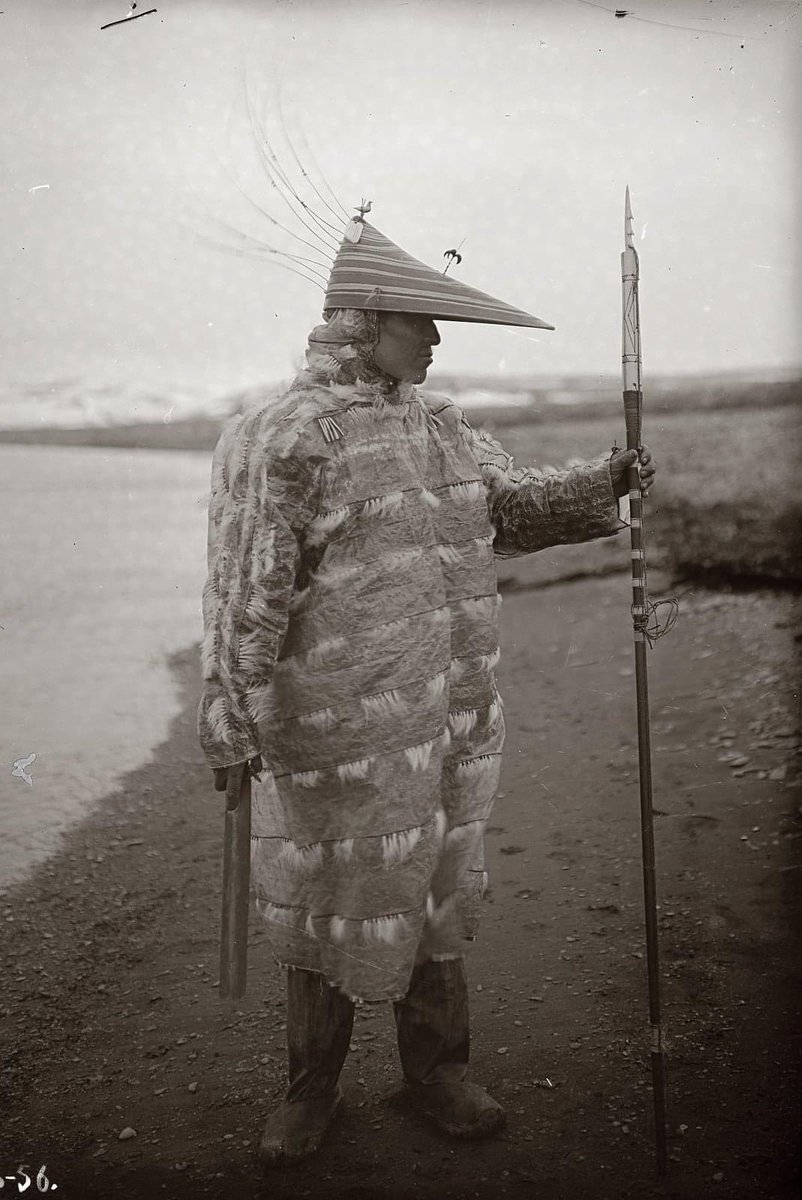 Unangax/Aleut hunter, Ivan Suvorov wearing a gut parka with a large harpoon, Umnak Island, Aleutian Islands, Alaska in 1909.  The visor is called a Chagudax, and was worn when hunting for seafood/sea residing animals on kayaks. It was in fact to block the sunlight.