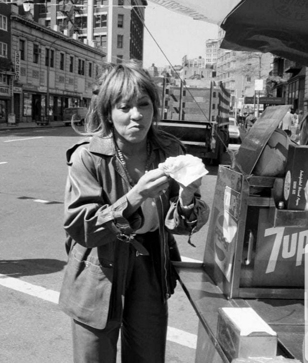 Looking North up 4th Avenue from 12th Street. The iconic Tina Turner stops for a dirty water dog from a Sabrett Hot Dog vendor in New York City. 1981