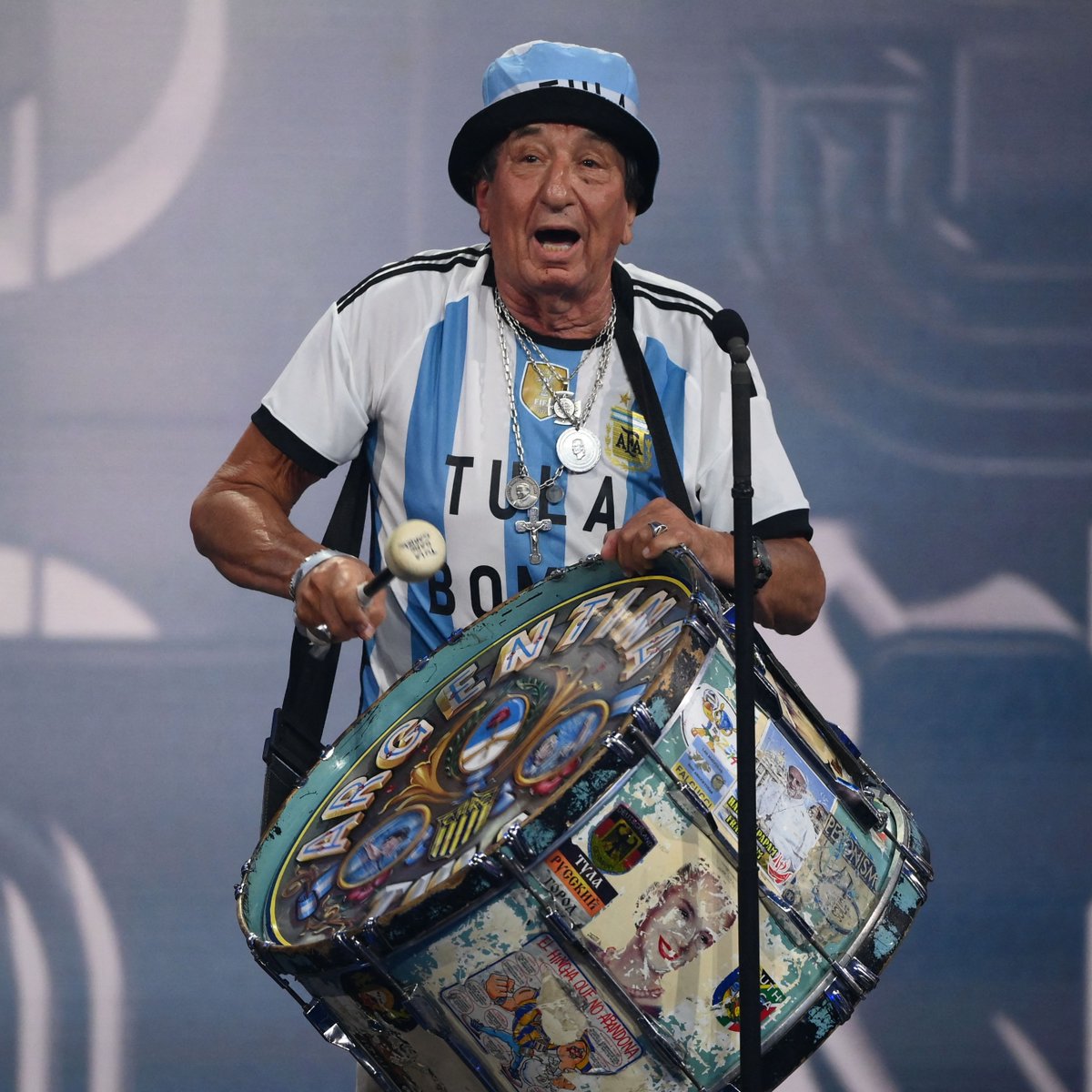 FIFAMuseum's tweet photo. Carlos "Tula" Pascual – together with his drum (“bombo”) he has attended 13 @FIFAWorldCups and seen @Argentina win it three times 🥁🇦🇷

He received #TheBest FIFA Fan award for all Argentinian fans last night. Do you think his “bombo” would look good in our exhibition? 🤔 https://t.co/Wuygpr6Ede