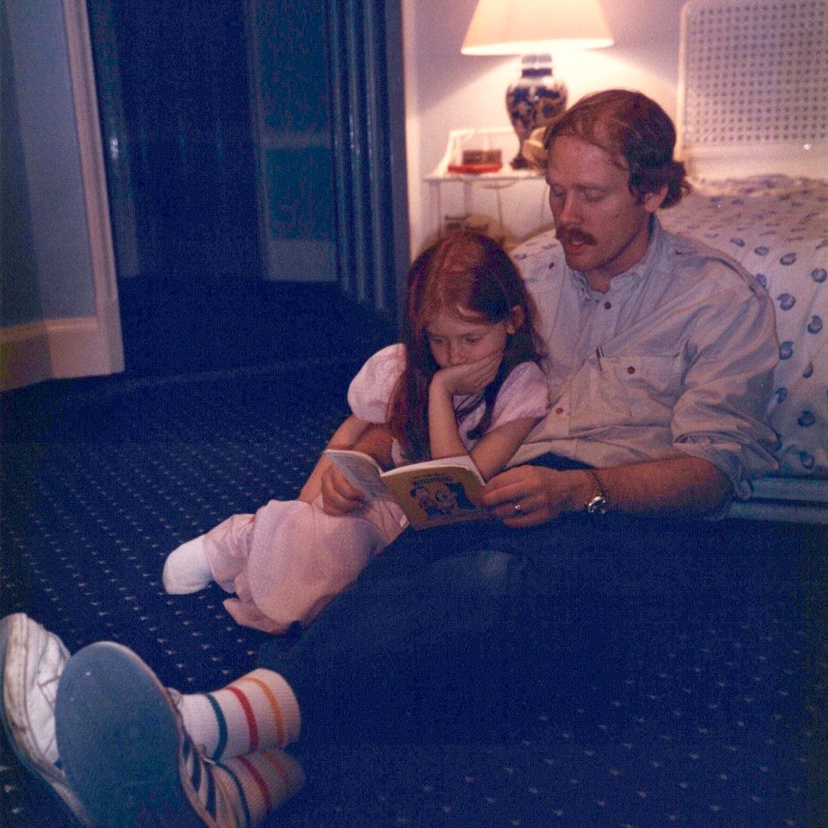 A bedtime candid from 1987. Ron (right) and BDH (left) sit on the floor, leaning against a bed as Ron reads BDH a book.