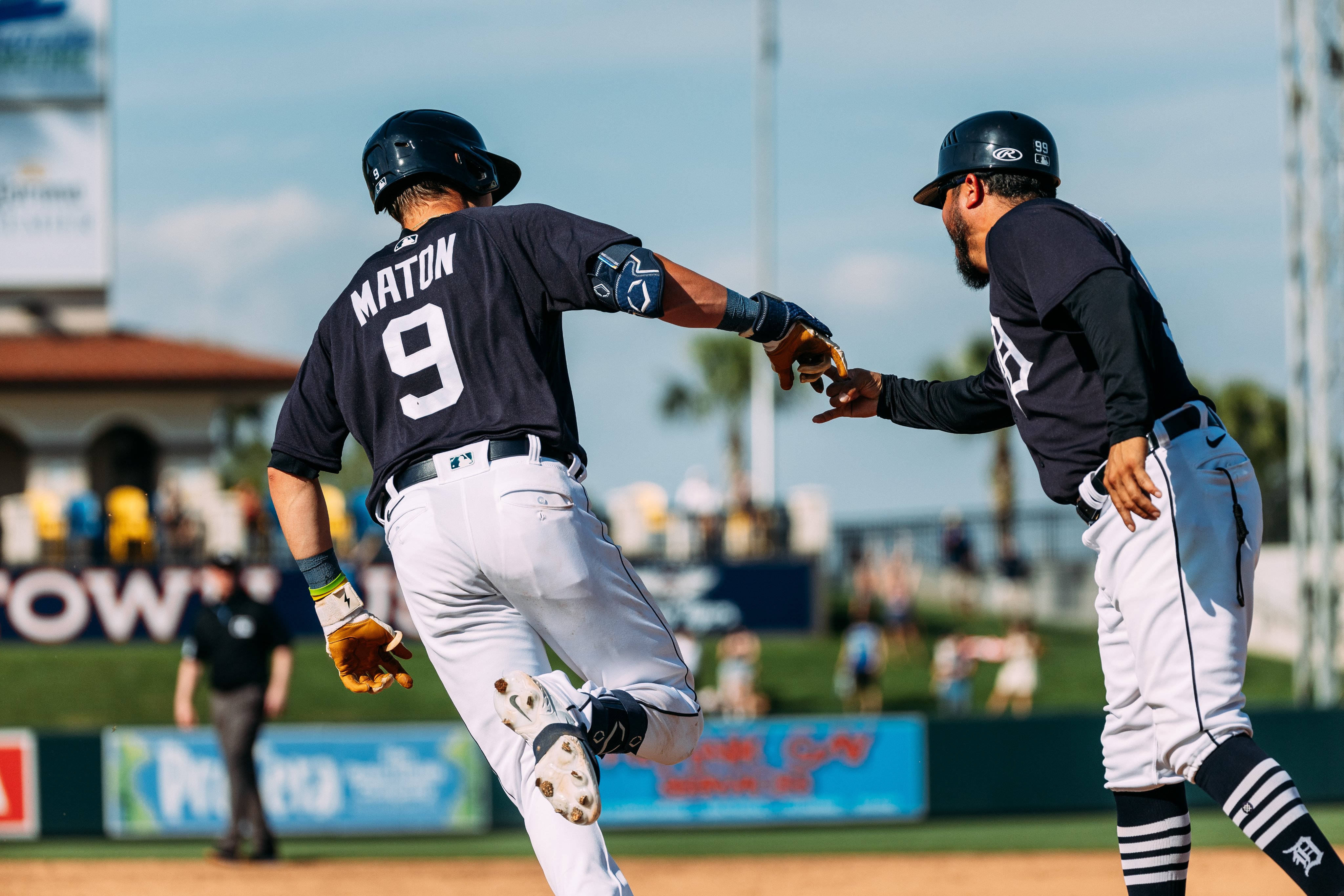 Nick Maton high fives first base coach Alfredo Amezaga as he rounds the bases