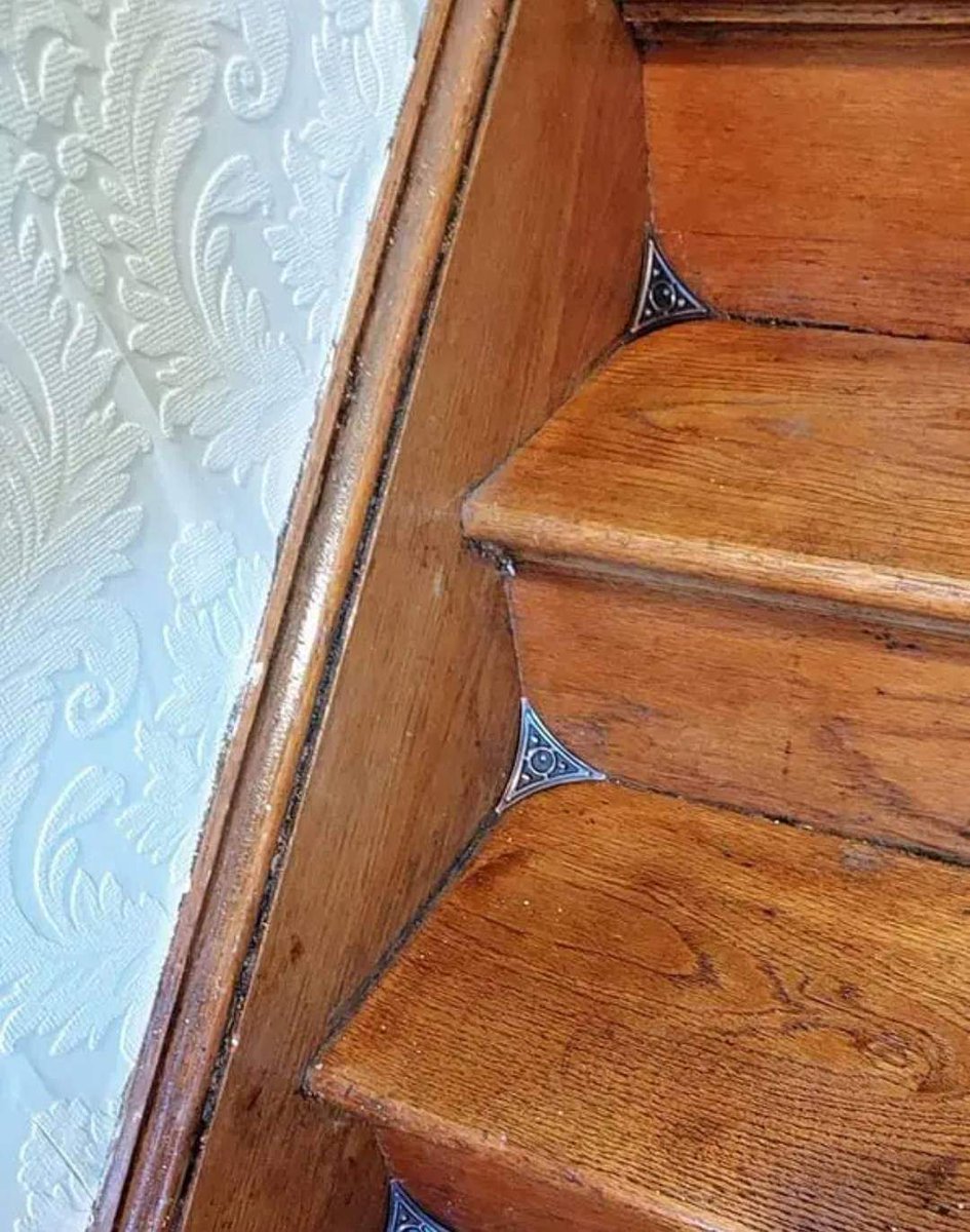 It is interesting :
Stair dust corners are flexible, triangle-shape pieces of brass or nickel that keep dust from accumulating in stair corners. They were introduced near the end of the 19th century as a way to simplify sweeping.