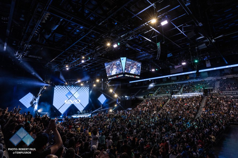 A crowd of people is gathered in the Michelob Ultra Arena during the Evo 2022 Finals. The photo includes the credit to photographer Robert Paul whose handle is @TEMPUSROB.