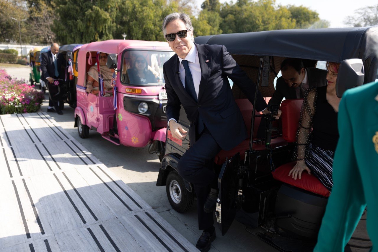 Secretary Blinken is stepping out of an auto-rickshaw. There are several auto-rickshaws behind the one he was riding in. 
