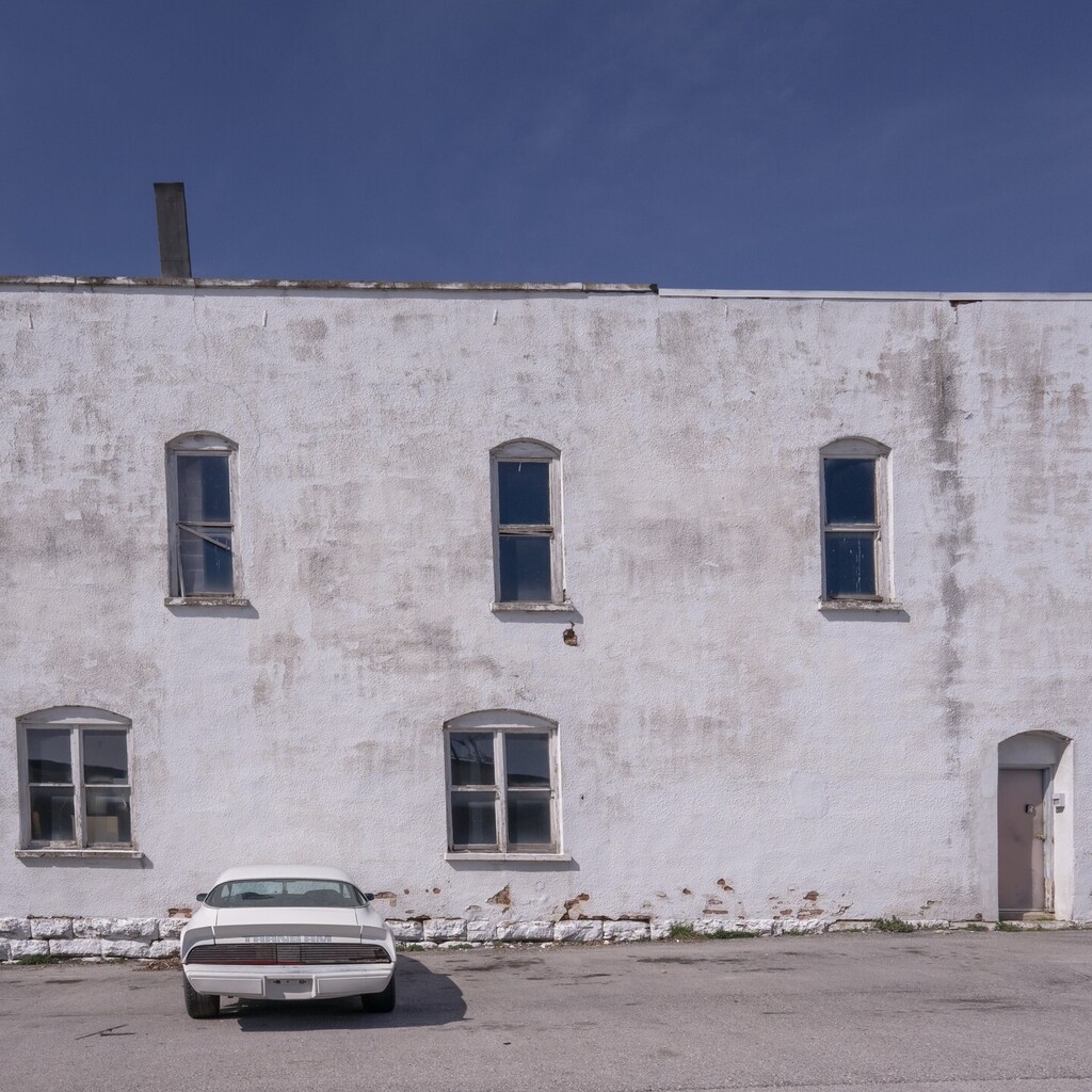 bobby_thompson's tweet photo. Took this a couple days ago while wandering around. I thought the white car against the white building might be interesting, but then decided I liked the bright blue sky added to the scene. #backroads #explore #smalltown #oldbuilding https://t.co/ki3DKK60HT https://t.co/2iK1p7XUA2