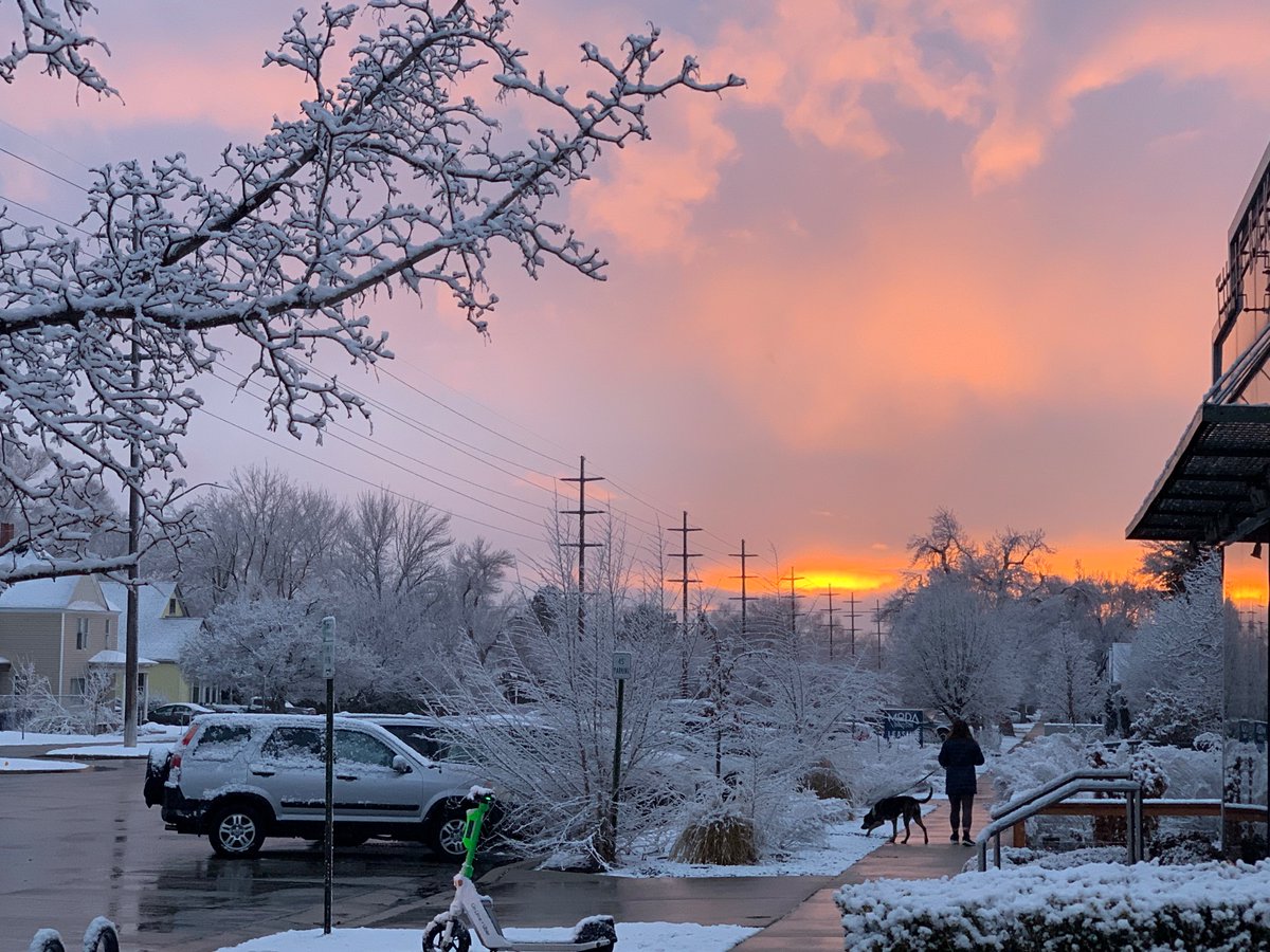 A street covered in fresh snow. Pink colored sunset in the backround.