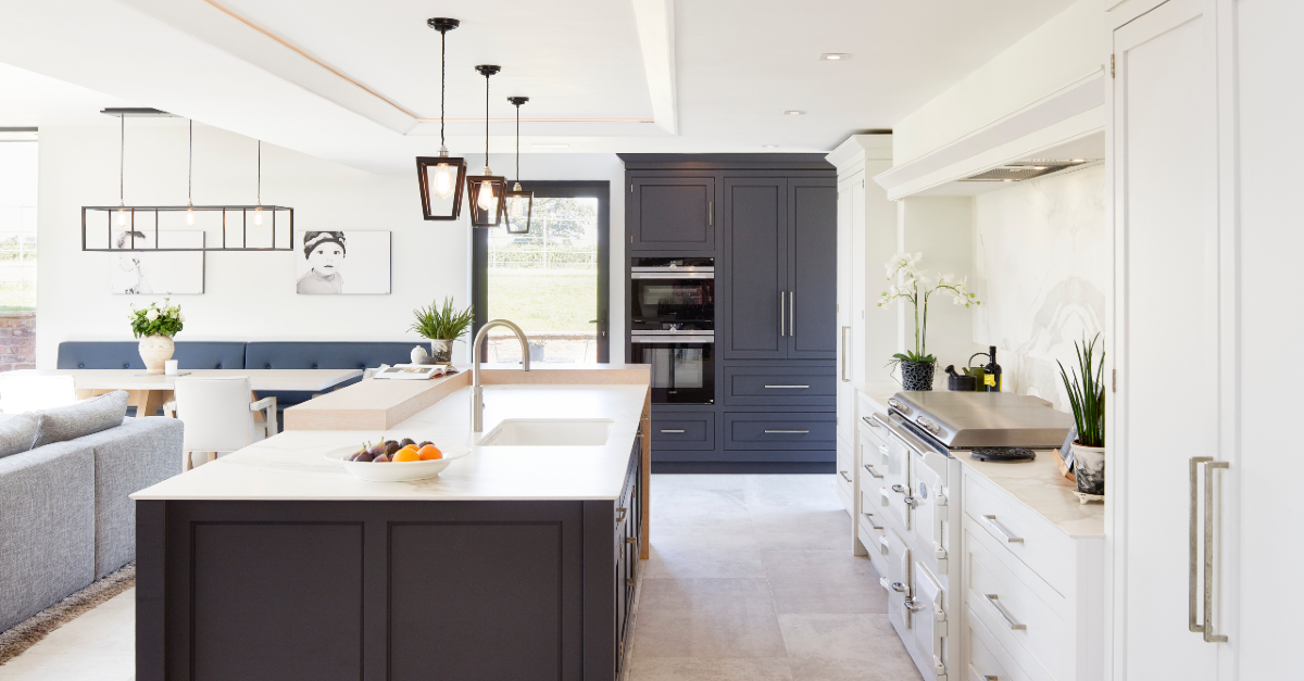 Open plan kitchen, living space w a cohesive palette of whites, greys & natural materials. An oak feature bar top adds warmth & a place to perch at the island. A well-planned lighting scheme allows flexibility to change the mood across the space with a range of fittings. #kitchen