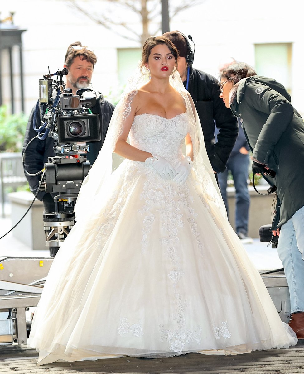 voguemagazine's tweet photo. .@selenagomez's recent bridal look may be pure fiction, but it's giving real wedding glamour. While filming season three of @OnlyMurdersHulu, the actress was spotted on set wearing a princess-style gown complete with a sheer veil. See the best veils here: https://t.co/wHc6esTpcA https://t.co/GSBALPNWPK