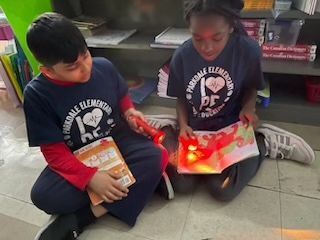 Students in SFA room 20 are enjoying buddy reading 📕 under the light of their flashlights 🔦.