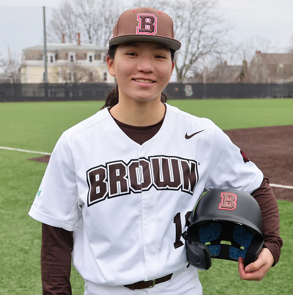 Brown University's Olivia Pichardo in uniform holding her batting helmet