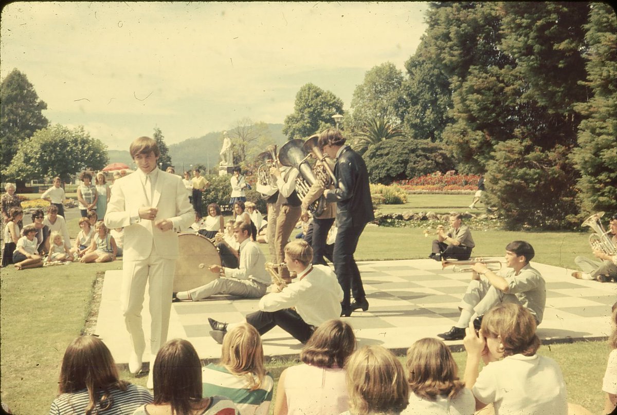 eric_riddler's tweet photo. #FoundSlideHoliday A local women’s marching team await their cue while Melbourne pop star Normie Rowe leads Auckland’s Rayders in a number for the movie ‘Don’t Let It Get You’, in Rotorua Government Gardens, Aotearoa New Zealand, slide developed March 1966 (photographer unknown) https://t.co/94XHR1QZSf