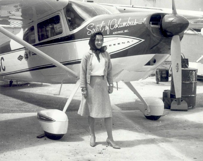 Black and white image of Jerrie Mock standing in front of the Spirit of Columbus. 