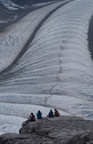 Ogives are bands of ice that alternate in both height and color and can be seen on a glacier’s surface. They are often shaped into arcs that point towards the bottom of the glacier. nsidc.org/learn/cryosphe… Photo credit: Allen Pope
