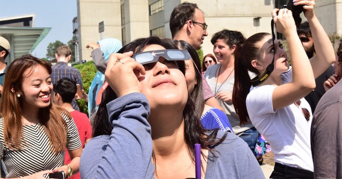 A group of people looking up at the sky with sunglasses.