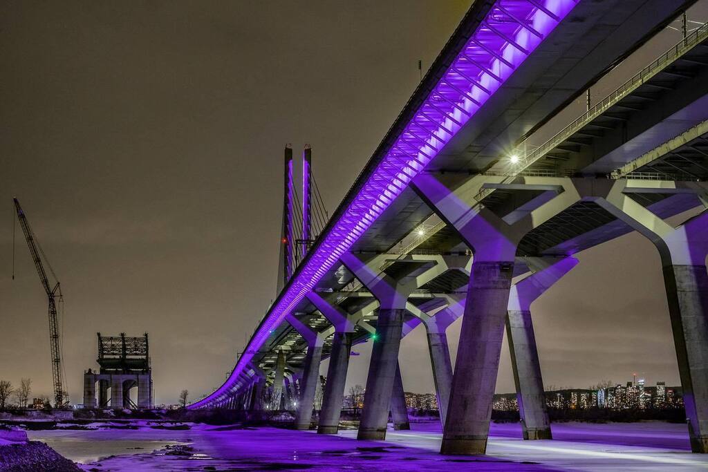 The Samuel De Champlain Bridge is lit in purple from sunset to 9 p.m. in Brossard on Tuesday March 14, 2023 in memory of the victims and all those affected by the tragedy in the town of Amqui, Quebec. At the left is what’s left of the former Champlain Br… instagr.am/p/CpyvcZPoUr-/