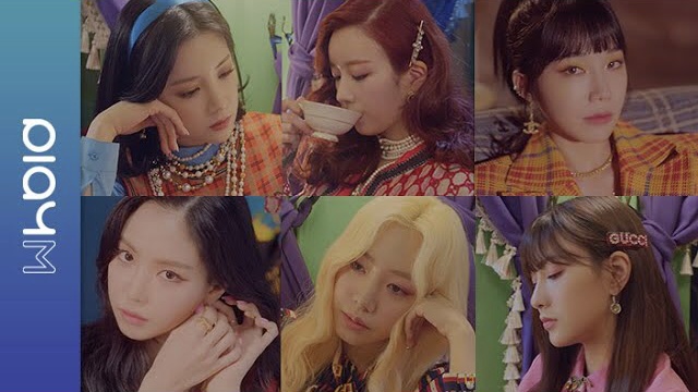 A promotional collage featuring six members of the K-pop group from their 'WHO IS' release, showing each member in colorful, fashionable outfits including plaid and patterned clothing with accessories.