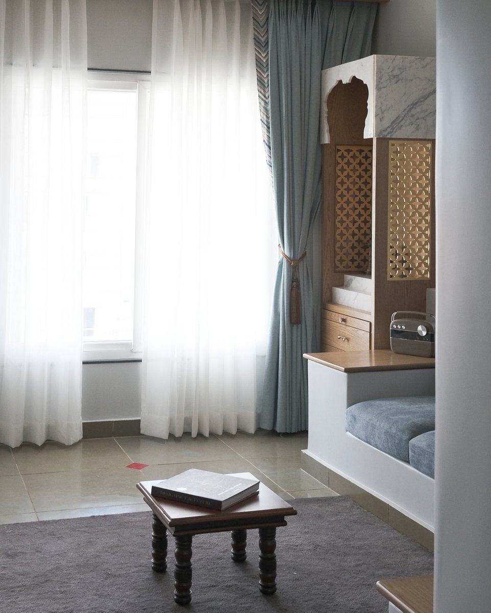 prashantkulsh's tweet photo. This cozy space is expertly curated with a concrete sofa, providing a modern and minimalist feel that perfectly balances the ornate mandir. The stone floor adds a natural texture to the space, further enhancing its earthy and grounded ambiance. This space is a perfect example of https://t.co/a4cHJPFNL5