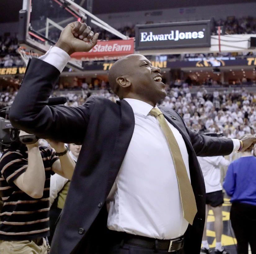 Dennis Gates fist pumps wearing a suit.