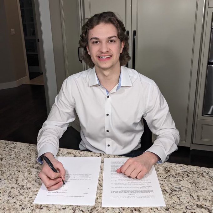 Photo of chase signing his contract and smiling