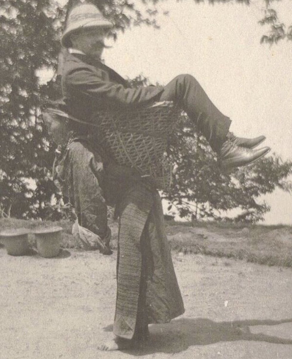 A British man is photographed as he is carried by a Sikkimese woman on her back in West Bengal, India, c. 1900