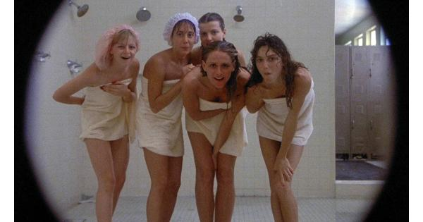 A still from the vulgar teen comedy "Porky's". Five women in towels stand as a group looking at a camera. There are shower heads behind them suggestive of a girl's locker room; there are also lockers visible to the side. The edges of the photo form a circle to suggest a peephole.