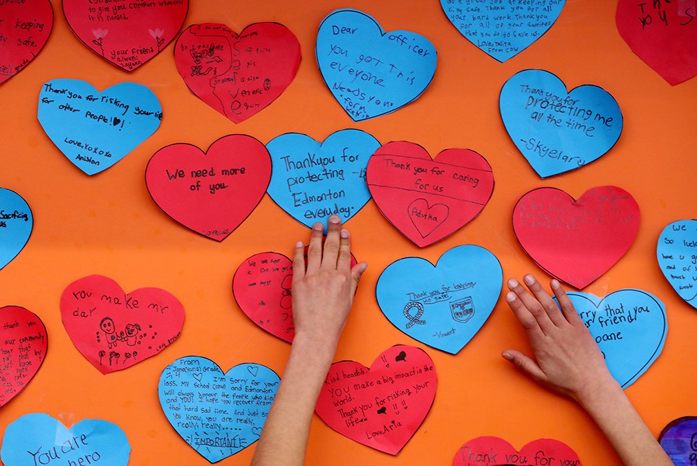 davidbloomphoto's tweet image. Grade 4 students at Const. Woodall School tie blue ribbons on a fence outside of the school in memory of Const. Travis Jordan and Const. Brett Ryan. Students have also posted heart shaped messages of support for police officers on a wall inside the school. #yeg @EPSBNews