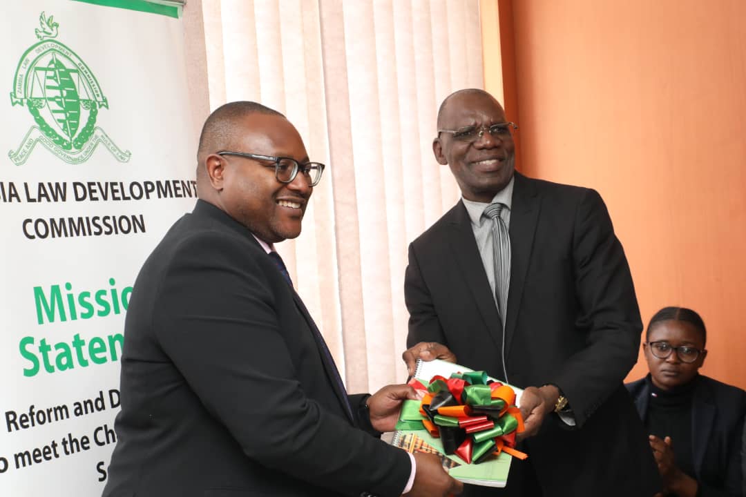 Minister of Justice, Hon. Mulambo Haimbe, receives the project report on the review of the British Acts ( Extension) Act Chapter 10 of the Laws of Zambia, from ZLDC Vice Chairperson, Munukuyumbwa Munyima