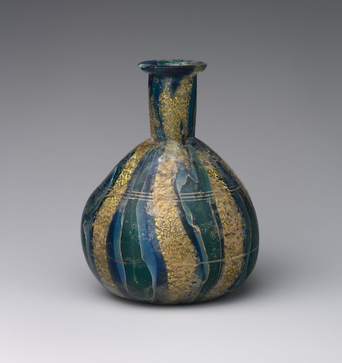 A #Roman glass bottle, in translucent blue, green & white glass encasing gold leaf, probably once used to hold scented oils or perfumes. It is about 2000 years old, but looks absolutely gorgeous, & apart from a few internal cracks, as good as new! (📷 NY Met Museum) #Archaeology