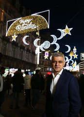 The Mayor of London stood in front of an illuminated sign with the words Happy Ramadan lit up alongside stars and moons.