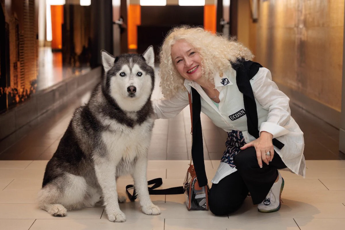 Photo of President Maric posing with Jonathan the husky