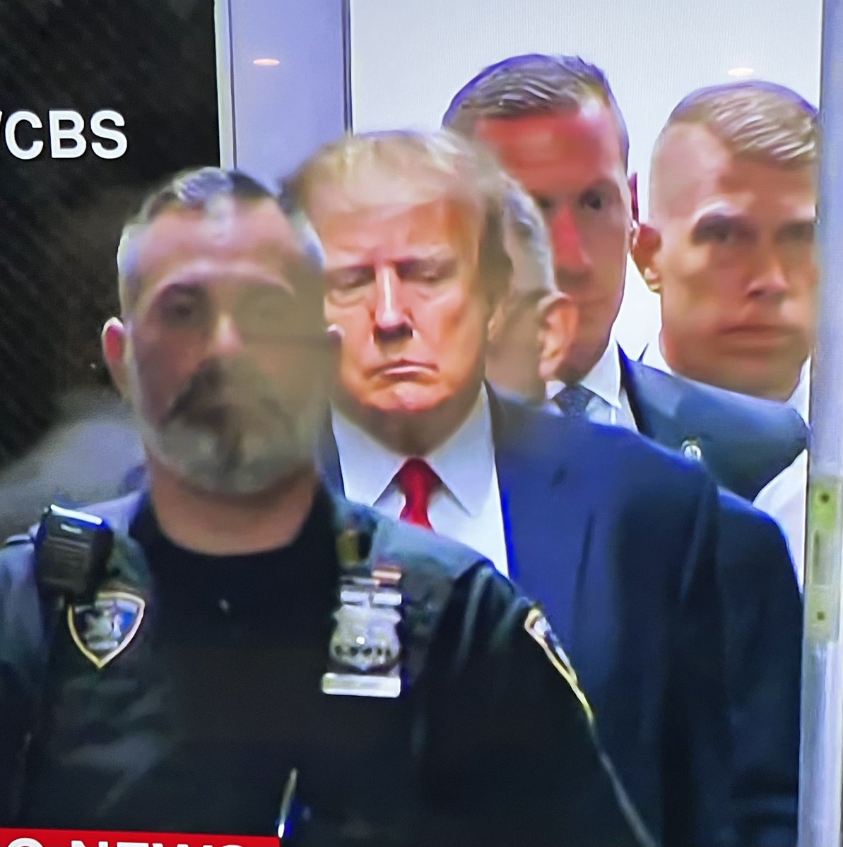 🚨MAJOR BREAKING: First photos have emerged showing Donald Trump entering the courtroom. 

Images show Trump sullen, quietly walking slowly accompanied by Secret Service and NY police officers. 

This is the first “perp walk” captured of a former United States president. 

He