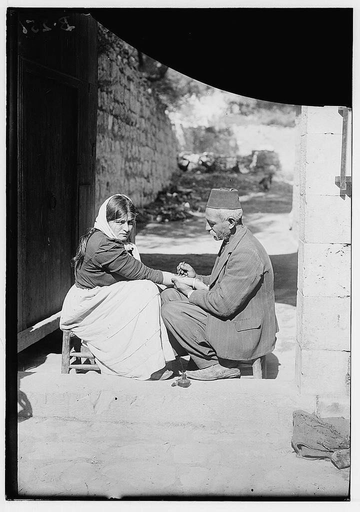 An Armenian refugee getting a tattoo on her forearm of the resurrection during Easter week in Jerusalem in 1921