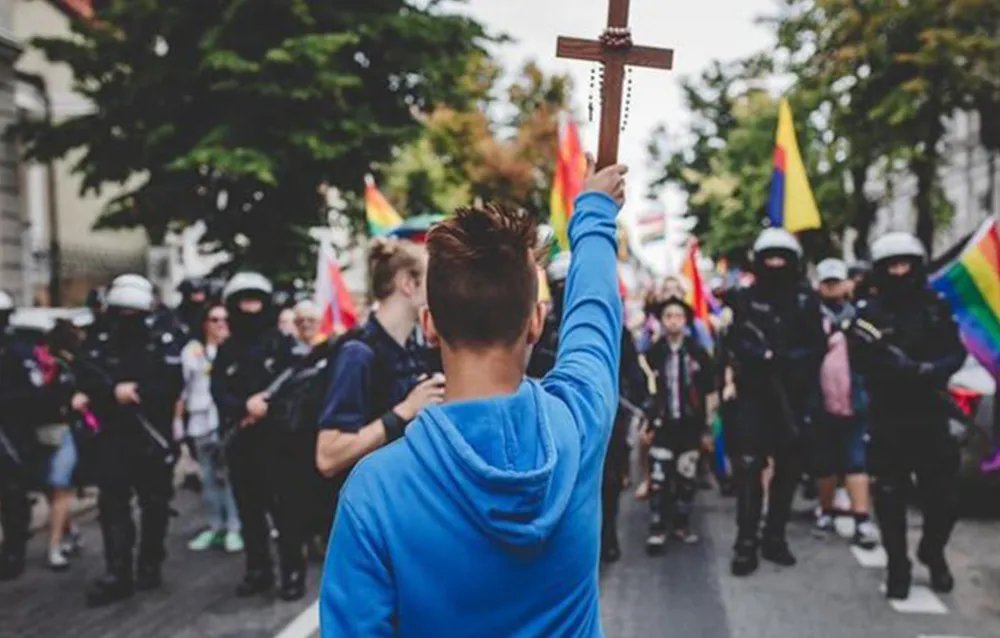 qriswell's tweet photo. Niño de 15 años con crucifijo en mano bloquea marcha LGBT, en la ciudad de Płock, Polonia. Para el joven este tipo de eventos no deben existir y por ello acudió a un crucifijo y rosario para "contrarrestar las malas acciones".

Oremos por más jóvenes como este. https://t.co/UeouIHnVQy