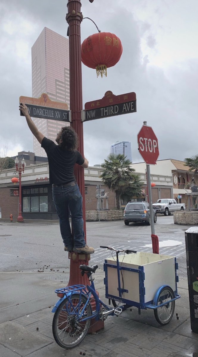 BikePortland's tweet photo. Our friend @Portlandpedals Ryan Hashagen stood on his trike to install a new sign on a block of NW Davis and 3rd that is now named NW Darcelle XV St. 

In memoriam of iconic drag queen Walter Cole - AKA #Darcelle - who died this week at age 92. 

pic by @familyride https://t.co/ohbwLUrXR7