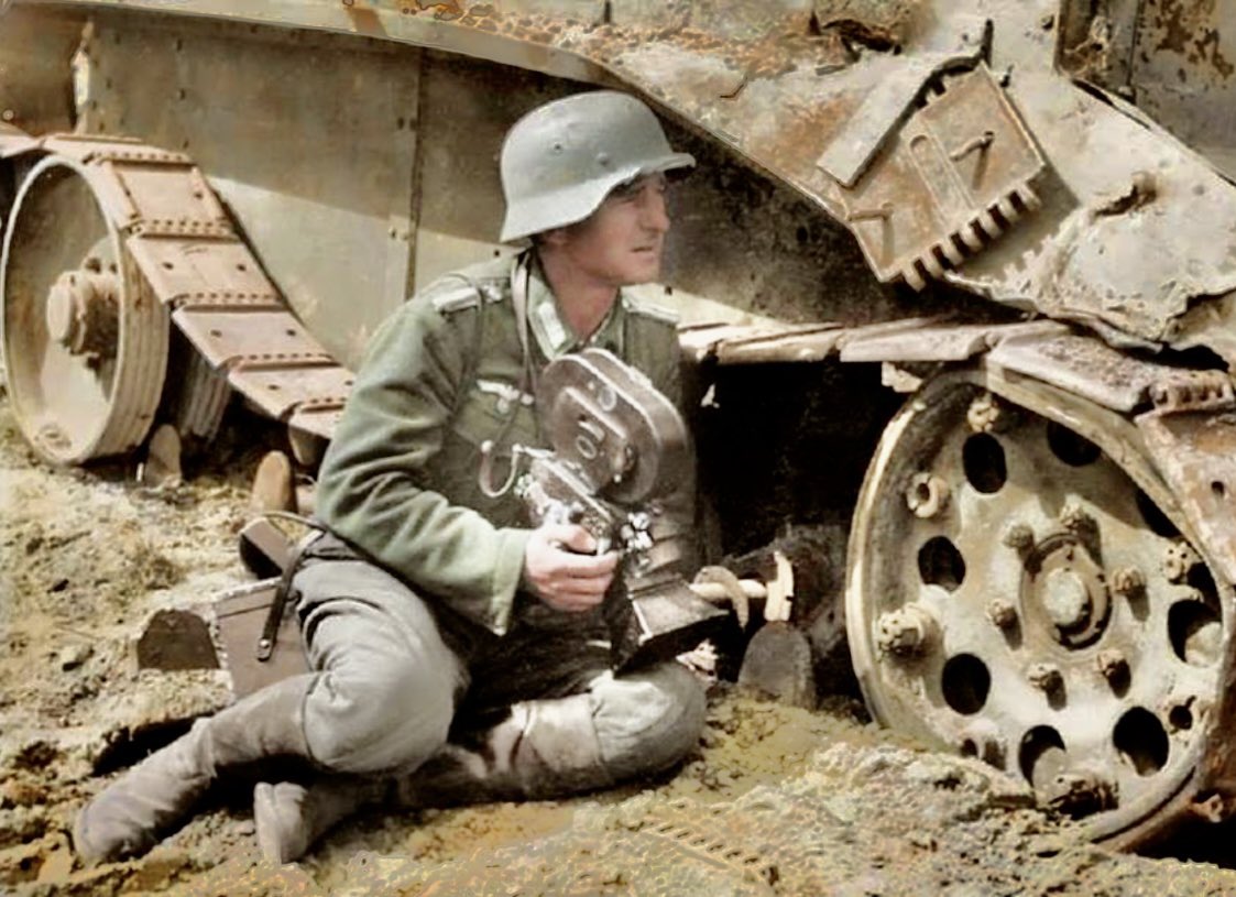 A German war correspondent (Kriegsberichter) with his Arriflex 35 2 35mm camera as he uses a knocked out Soviet BT-5 light tank for cover - exact date and location unknown. Colour byRoyston Leonard #ww2 #worldwar2 #kreigsberichter #correspodent #cameraman #camera