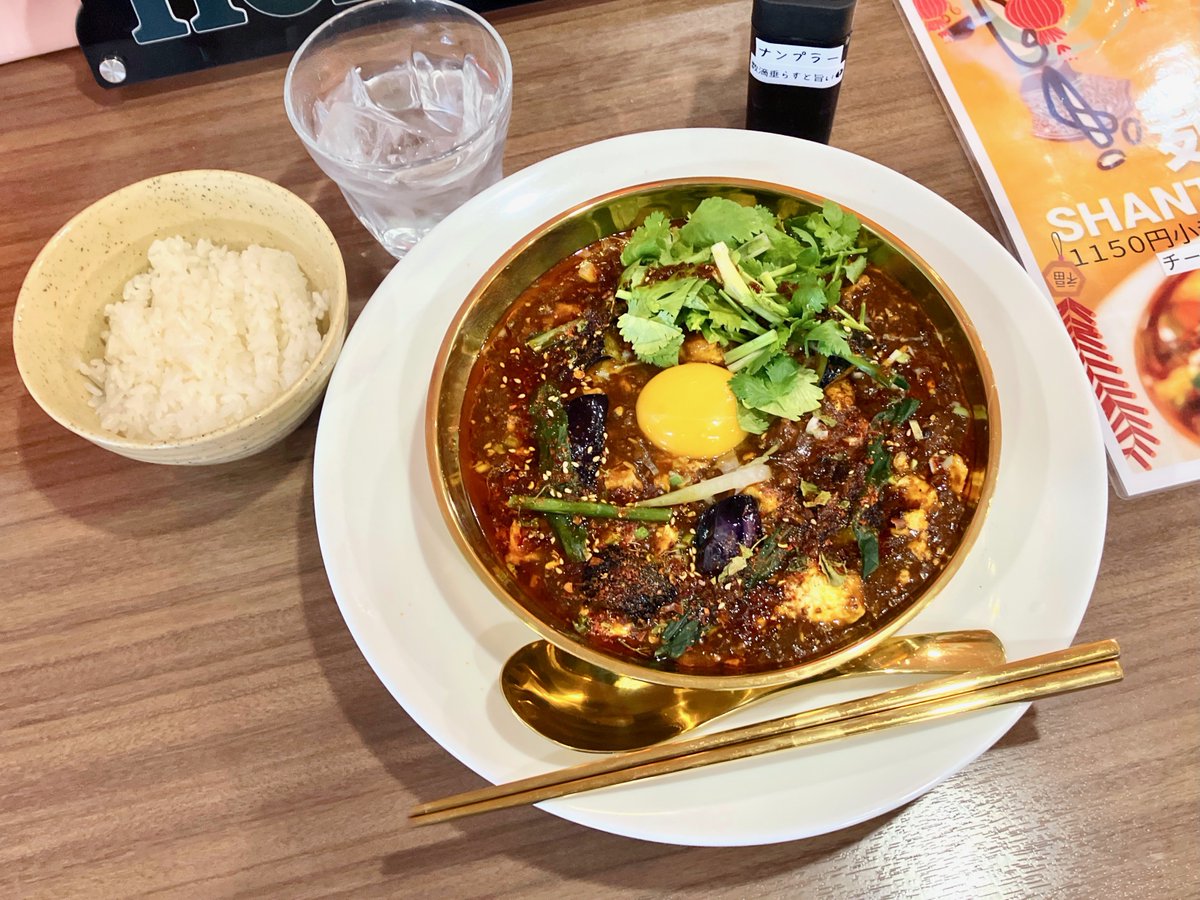 豊平『SOUP CURRY & NFT ART SHANTi』行者羊咖哩羊麻婆拉麺+パクチー 中央に卵黄、隣にパクチーが配されて、麻婆具材は行者にんにく・粗挽きラム・豆腐・茄子・葱・白胡麻。 トロミを纏った餡が重く、麺を引っ張り出すにも入り、言い方