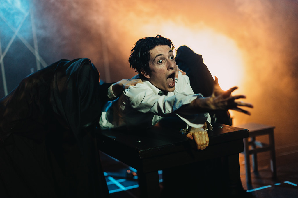 A photo from the Scottish Play - a performer shouts with a bright light in the background. 