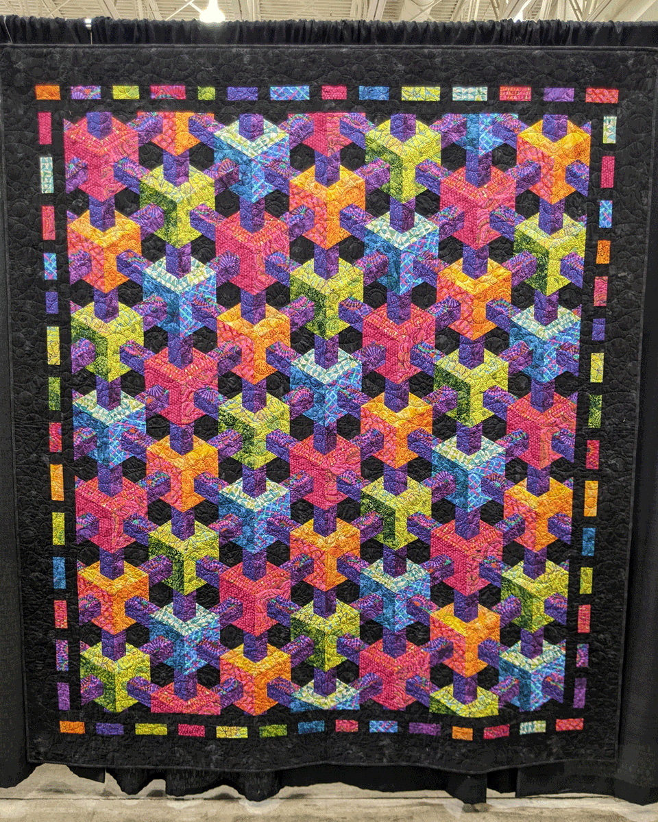 WIQuiltShow's tweet photo. "Escher Connected," created by Dee Van Driel of Fitchburg, Wisconsin and quilted by Mary Vassalotti, entered in the 2022 Quilt Contest, Machine Quilted Bed Size - Pieced category. Pattern/design source: "Escher Connected" by Christopher Weinhold. #WisconsinQuiltShow https://t.co/yOh1wWzHLT