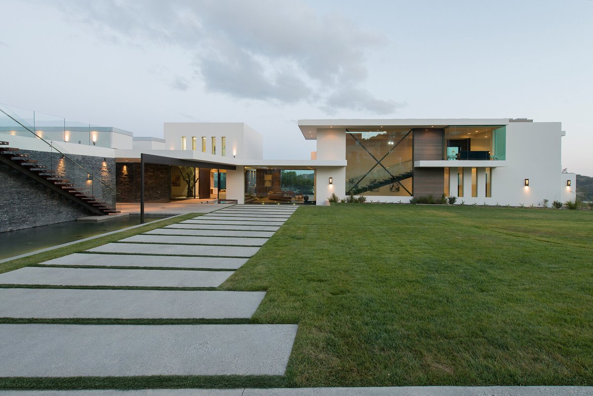 At our Benedict Canyon House horizontal pavers guide the eye towards the center of the home, where floor to ceiling glass walls + ribbon windows create a sun filled gallery inside. Photo by @maccollum

#exterior #exteriors #exteriordesign #modernexterior #luxuryexterior #mansion