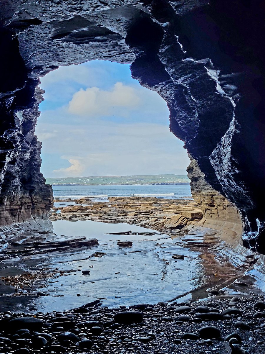 Blue seas and skies framed in a seacave mouth on Ireland's Atlantic coast.  County Clare, Ireland.