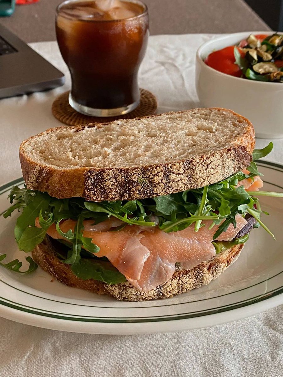 A breakfast of salmon on a sandwich with vegetables and a glass of cappuccino makes for another full and satisfying day