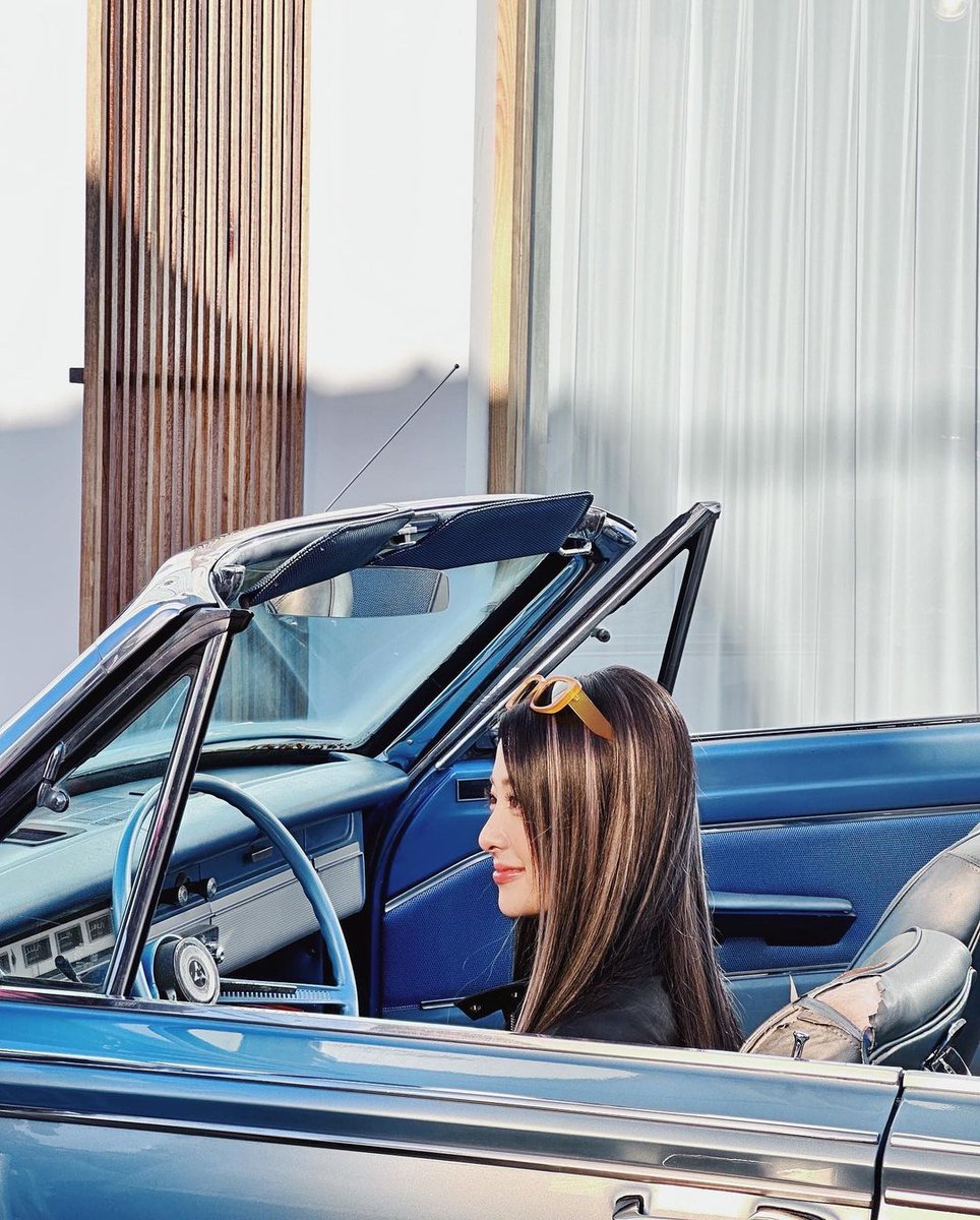 Behind the wheel, this stunning girl was silent. Her hair is flowing nicely as the breeze caresses it, giving her a really hot appearance. This time, she also puts sunglasses to her appearance. 🌟
