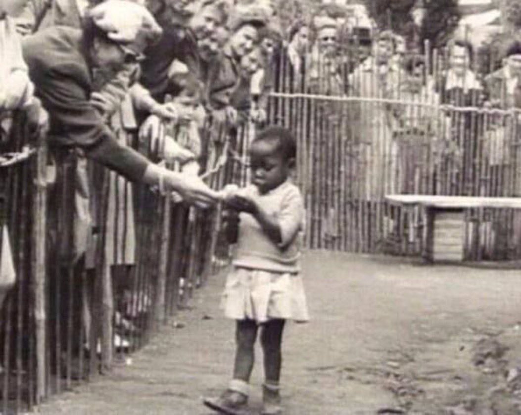 1958 in Belgium when an African girl was kept in a zoo as a monkey to attract tourists. ‘Civilized’ people feeding a banana to an African girl in a human zoo during a World Fair in Brussels.