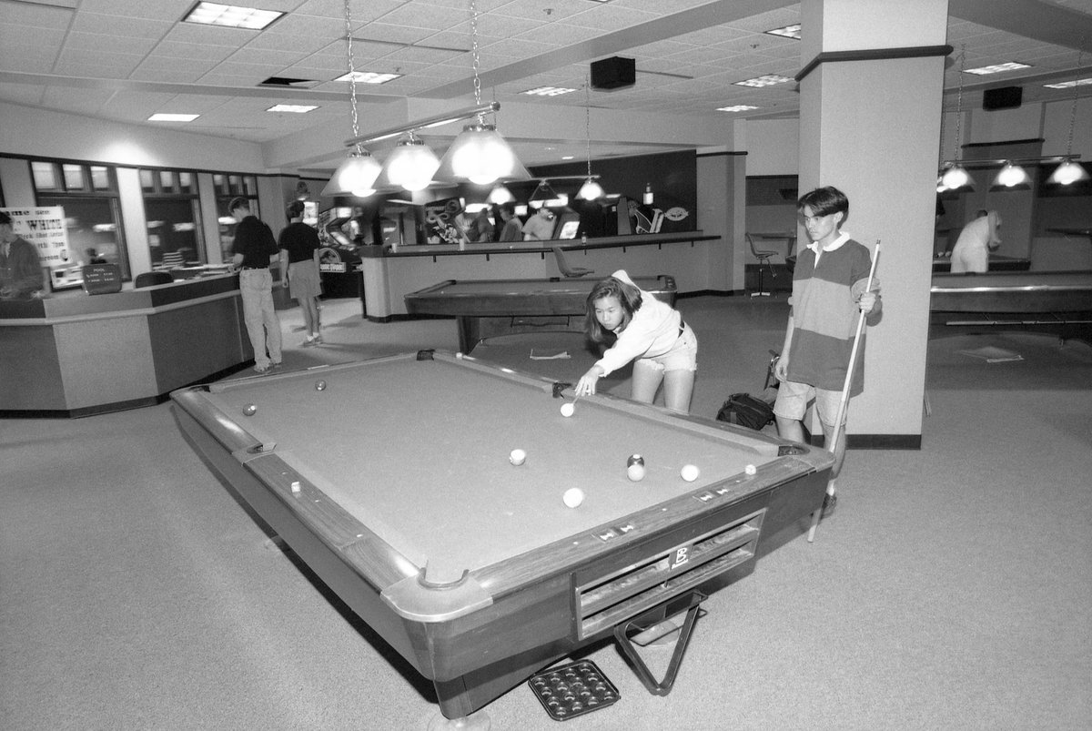 Students play pool in the game room on the east side of the first level of the Alumni Memorial Union in 1993. In the background, students can be seen playing video games.
- MU Archives
