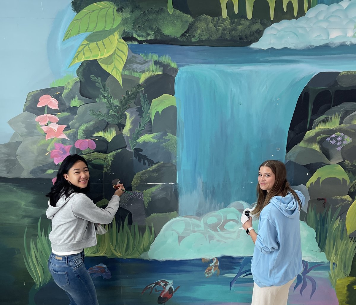 SAES's tweet photo. As part of a unit on art restoration, students from Lauren Cook’s Advanced Painting class had the opportunity to refresh artwork on campus. Before Spring Break, Emma Kee ‘24 and Kate Hudgins ‘25 restored sections of the Derek Park Memorial Mural made by Noa West ‘15. https://t.co/LhegaFTq6P