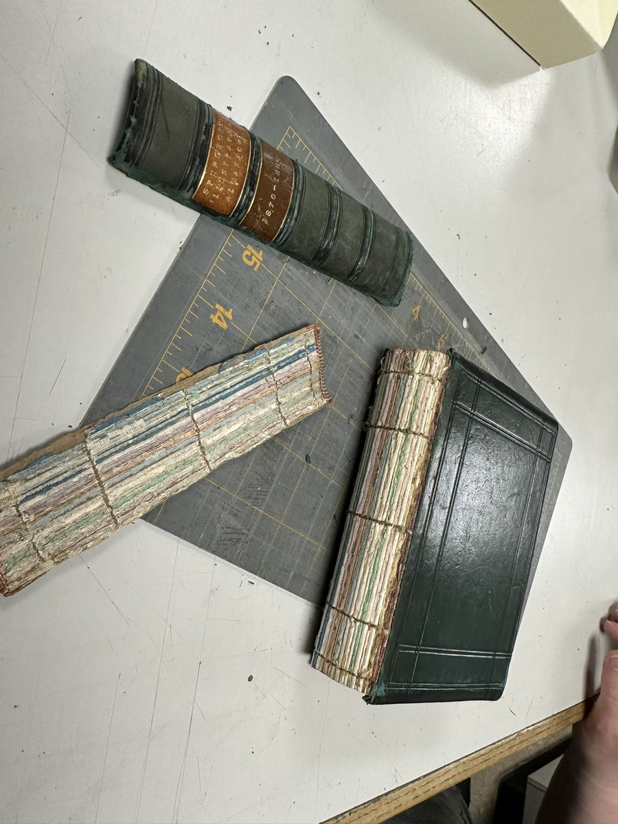Next steps in the conservation. Lifting leather on cover with spatula to insert new leather hinge. Create small notch- so new hinge will wrap correctly. Detached spine  to be reconditioned. Book is collection of pamphlets bound with sawn spine now loose &amp; needs to strengthened.
